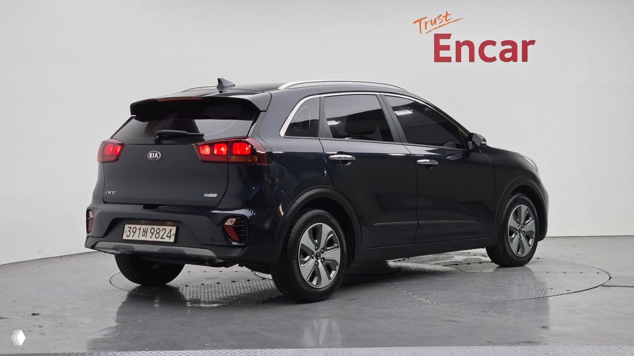 KIA The New Niro 2021 — задний трёхчетвертной ракурс тёмного кроссовера на студийном подиуме, видны задние фонари и корейский номер.