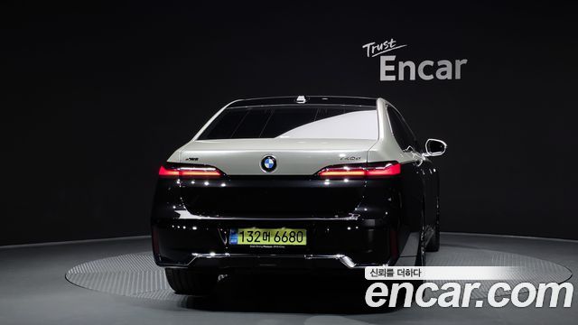 Вид на заднюю часть BMW 7 Series 740d xDrive M Sport 2025 в шоуруме: фон и подсветка подчёркивают линии кузова и светотехнику.