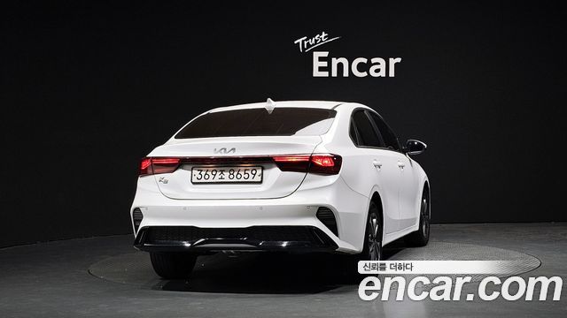 Ещё один вид сзади белого Kia K3 2022 в выставочном пространстве Encar — задняя оптика и бампер на чёрном фоне.