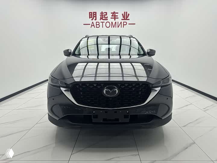 Передняя проекция Mazda CX-5 2026: крупный вид спереди с решёткой радиатора и логотипом, автомобиль в светлом шоуруме.