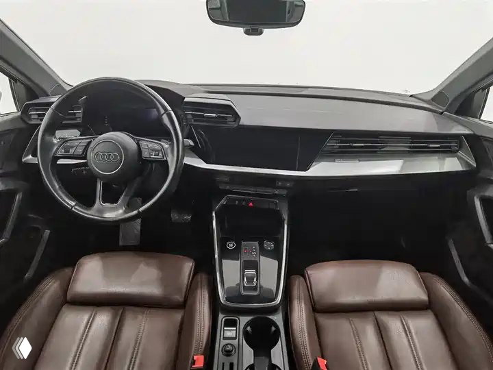 Интерьер Audi A3 Sportback 2022: передняя панель, мультифункциональный руль, центральная консоль с селектором и коричневые кожаные сиденья — вид из водительской зоны