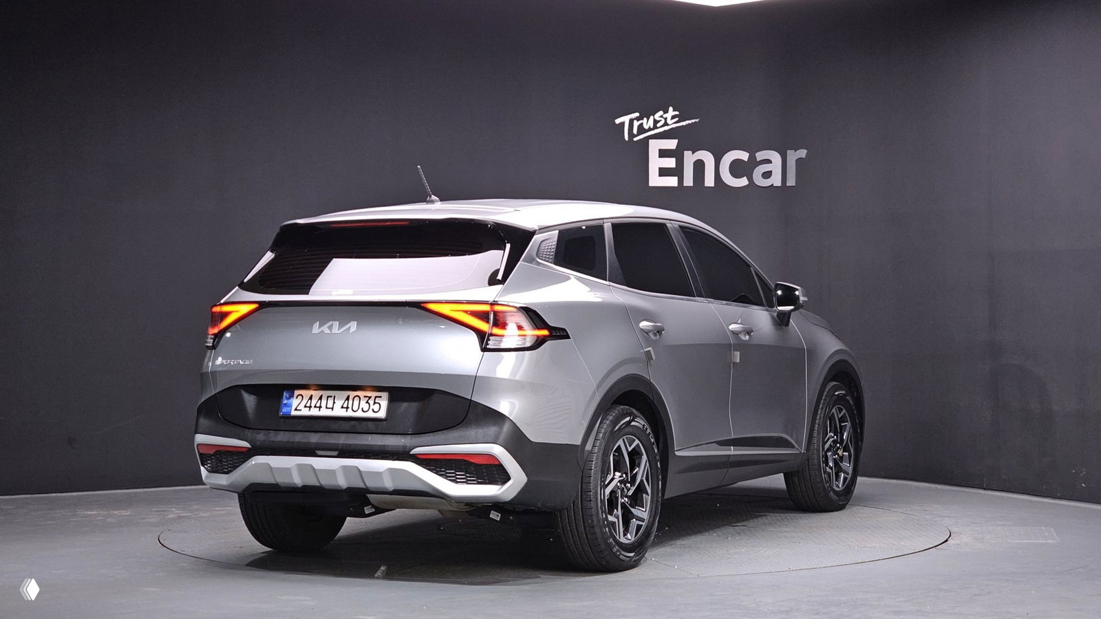 Kia Sportage 5 2023 вид сзади-скоса в студии: яркие задние фонари, форма багажника и бампера, на машине корейский номер и отражение фона.