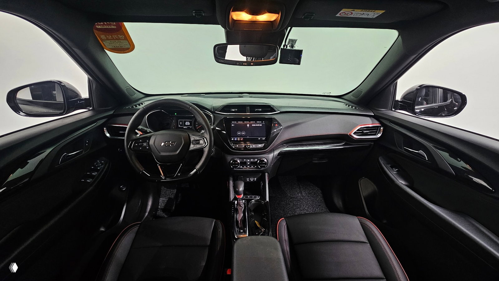 Интерьер Chevrolet Trailblazer RS 2021: вид на приборную панель, мультимедиа, руль и кожаные сиденья с контрастной прострочкой, студийная подсветка и общий салонный план.