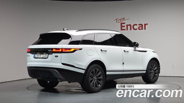 Белый Range Rover Velar, вид сзади под углом в шоуруме Encar, видна задняя оптика, номер и объём багажной части, автомобиль на обзорной площадке