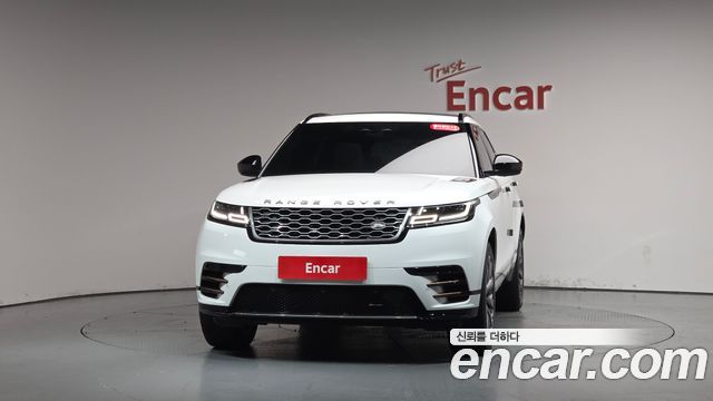 Передний вид белого Range Rover Velar в студии, крупный план на фактуру решётки, бампер и фары, автомобиль показан целиком спереди