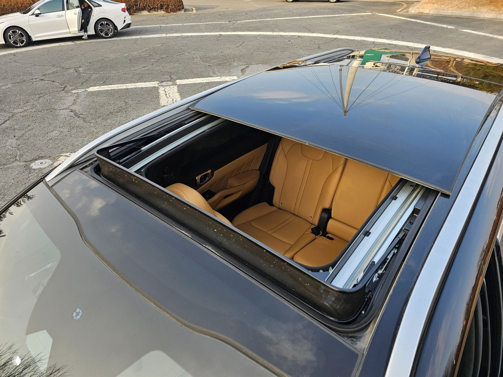 Открытый панорамный люк KIA Sorento — вид сверху на передние сиденья бежевого цвета и конструкцию сдвижного стекла в крыше автомобиля.