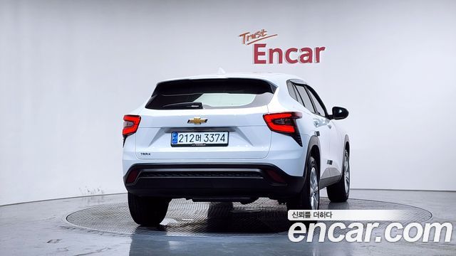 Вид сзади белого Chevrolet Trax 2024 в Encar, показаны фонари и задняя часть кузова; изображение подчёркивает состояние и элементы экстерьера автомобиля.