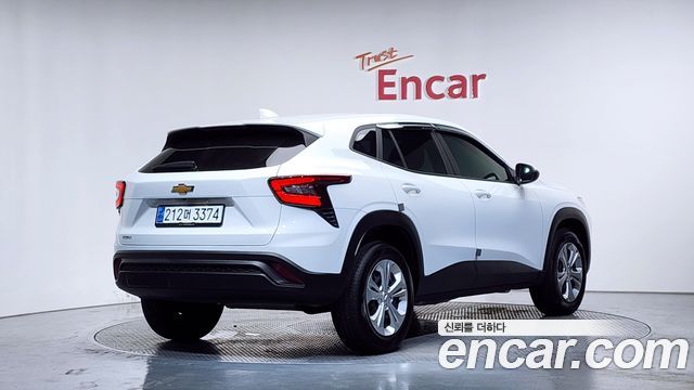 Chevrolet Trax 2024 белого цвета, вид сзади-право в шоуруме Encar; видно задние фонари, бампер и корейский номерной знак, демонстрация состояния кузова.