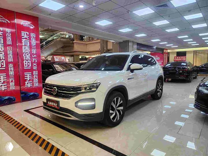 Белый Volkswagen Tayron 2021 (Китай) в автосалоне: вид спереди-слева, полированный кузов, другие машины на фоне.