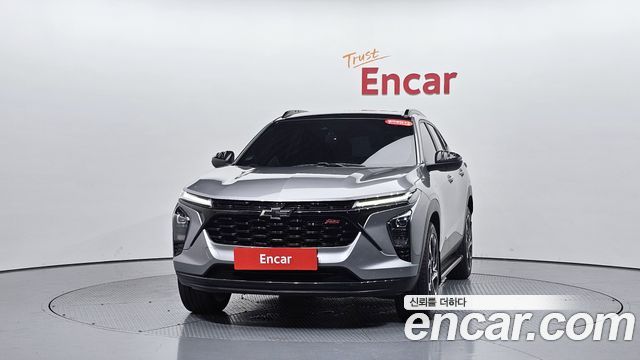Chevrolet Trax 2024 (Корея) — вид спереди в студийном павильоне Encar: решётка радиатора, фары и красная табличка Encar на фоне.