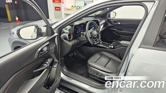Интерьер Chevrolet Trax 2024 — водительское место с рулём, приборной панелью, центральной консолью и сиденьем в подготовленном шоуруме.