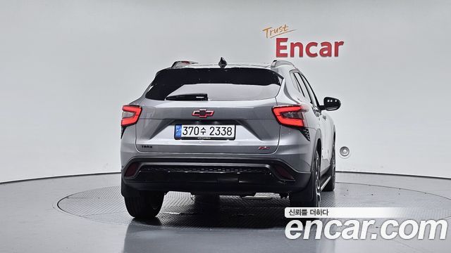 Chevrolet Trax 2024 — вид сзади по центру в шоуруме Encar: задняя дверь, фонари и вращающаяся платформа для демонстрации авто.