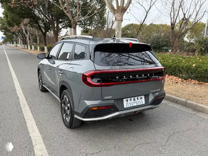 Задний вид Hyundai ix35 2023 серого цвета на дороге, видна задняя LED-оптика, шильдик модели и китайская номерная табличка