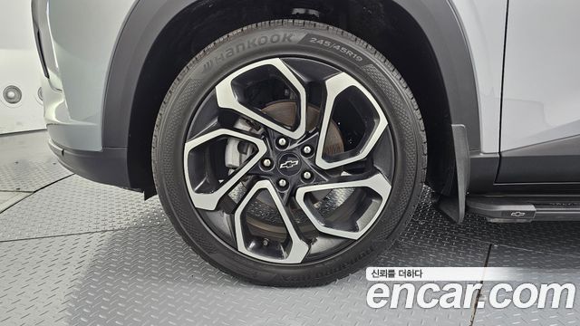 Детальный вид колеса и легкосплавного диска Chevrolet Trax 2024 — протектор шины, рисунок диска и часть кузова на фоне студии Encar.