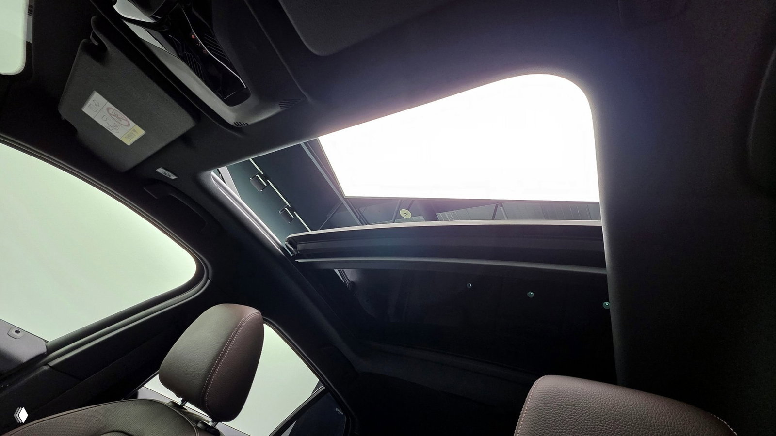 Вид вверх на панорамный люк крыши BMW 1 Series F40 — раскрытый срез крыши и внутренний обивочный контур подстекольной области салона.