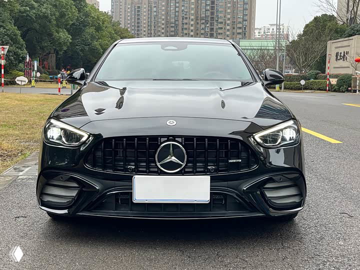 Mercedes‑Benz C 260 L 2023 — вид спереди: решетка радиатора, фары и номерной знак, темный кузов на фоне жилой застройки.