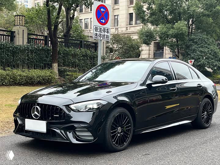 Черный Mercedes‑Benz C 260 L 2023, крупный план бокового ракурса и передней части, автомобиль на городской парковке около жилых зданий.