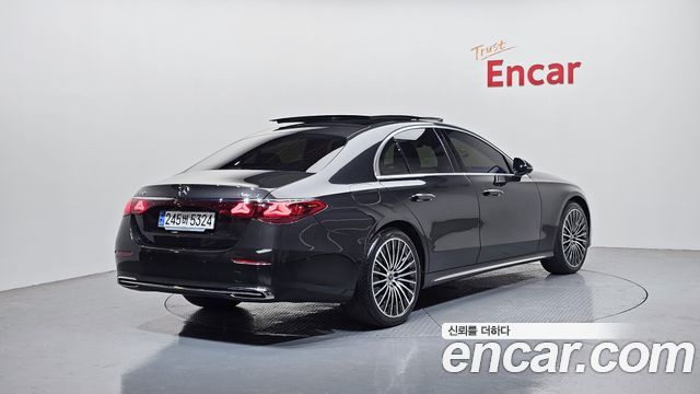 Фото Mercedes-Benz E-Class E450 2024 сзади под углом, тёмно-серый кузов, видны задние фонари, диски и часть боковой линии кузова