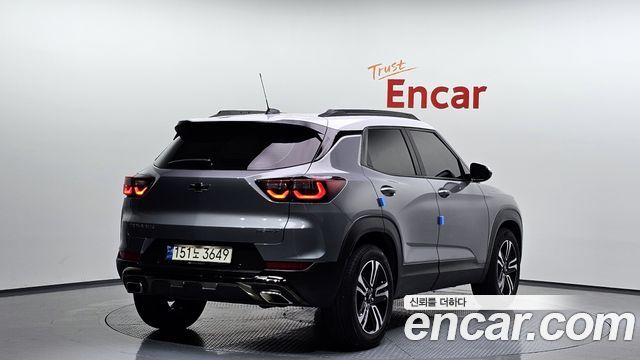 Вид сзади на Chevrolet Trailblazer 2024: буквы и фон шоурума Encar, задние фонари и кузов автомобиля в сером цвете.