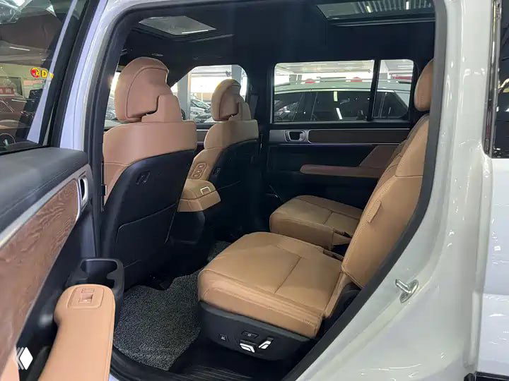 Задние сиденья Hyundai Santa Fe 2024: коричневый кожаный салон, просторный второй ряд, вид на коврики и дверную сторону в автосалоне.