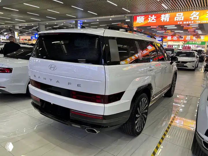 Задний ракурс белого Hyundai Santa Fe 2024 в автосалоне Китая: вид на корму, светодиодные фонари и соседние автомобили на стенде.