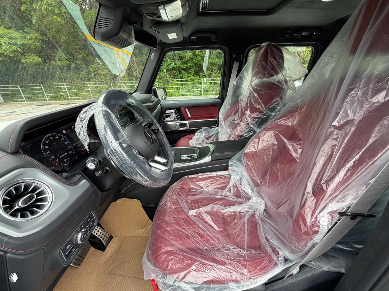 Интерьер передней части салона Mercedes‑G63 2026: руль, приборная панель и передние сиденья закрыты защитной плёнкой перед отправкой из Кореи.
