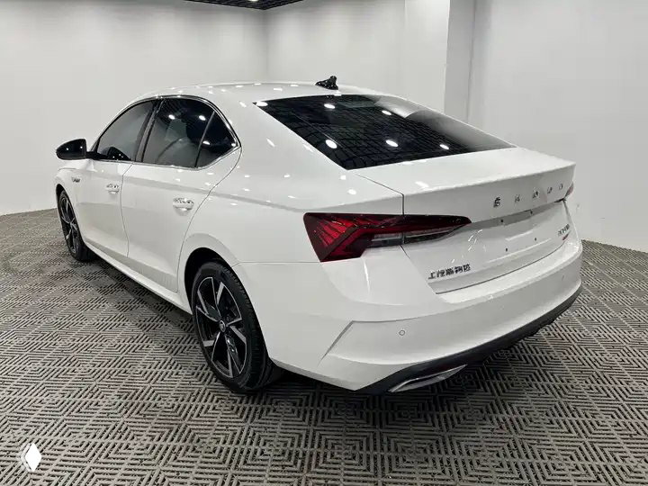 Задняя часть белой Skoda Octavia PRO TSI280 2021 (Китай) в шоуруме: вид кормы, фонари, шильдик OCTAVIA и элементы бампера на светлом фоне.