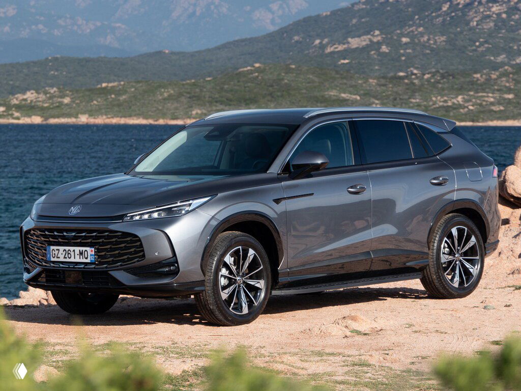 Серый кроссовер MG у побережья, трёхчетвертной вид спереди; подчёркнутые линии кузова и дизайнерские колёсные диски на фоне моря.