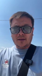 Видео-превью: мужчина в солнцезащитных очках снимает себя на фоне ясного неба, видна лямка ремня безопасности и часть камеры, фрагмент видео с клиентом.