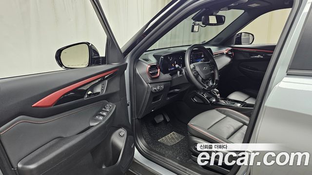 Интерьер Chevrolet Trailblazer 2024: передняя кабина, руль, панель приборов и водительское кресло; салон в тёмной отделке с акцентами.