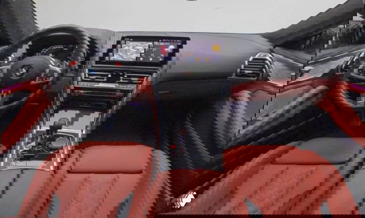 Салон BMW M8: передние сиденья из красной кожи, руль с эмблемой BMW, центральная консоль с мультимедийным экраном и элементами управления.
