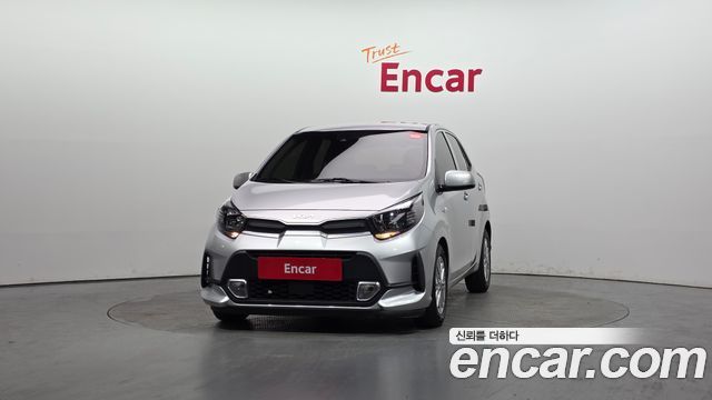 Kia Morning Signature 2021 в автосалоне Encar: фронтальный вид автомобиля на белом фоне, видны передняя решётка и фары.