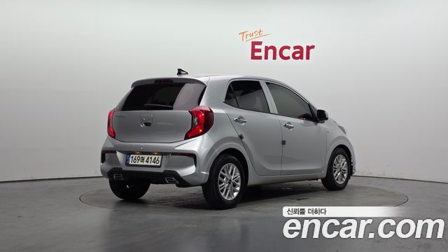 Kia Morning Signature 2021: задний правый ракурс автомобиля в студии Encar, вид на фон, светлую окраску и номерной знак корейской регистрации.