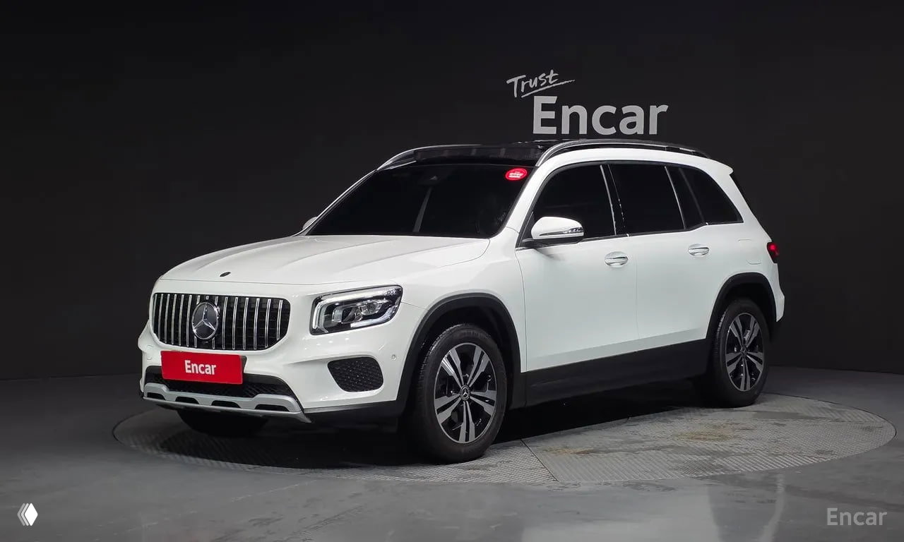 Белый Mercedes‑Benz GLB‑Class 2021 в студии Encar: фронтальный трёхчетвертной ракурс, видны решётка радиатора и фасад кузова.