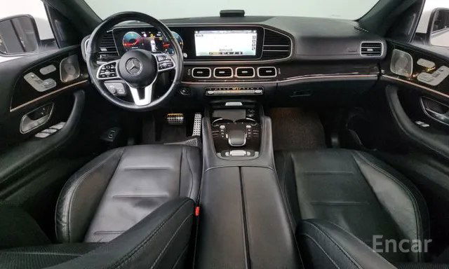 Салон Mercedes GLE: панель приборов и центральная консоль с экраном мультимедиа, кожаные сиденья и элементы отделки в кадре.
