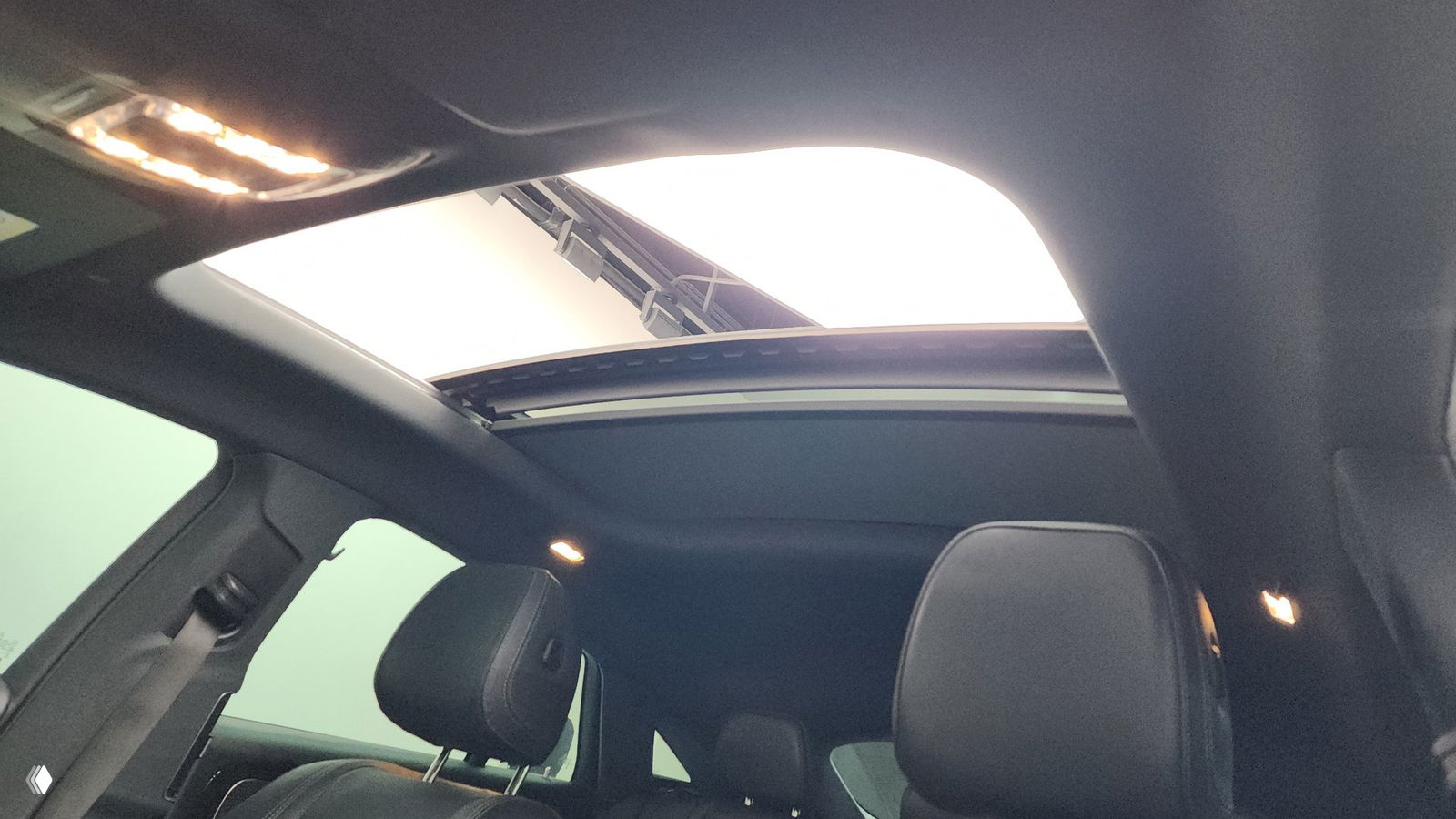 Вид потолка и панорамного люка Mercedes GLE из салона, видно открывающийся люк, подсветку и верхнюю часть передних кресел.