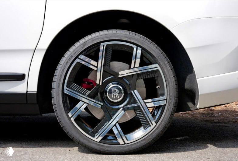 Крупный план колеса и диска Rolls‑Royce Cullinan с эмблемой RR; деталь колёсного диска и тормозной суппорт видны чётко.