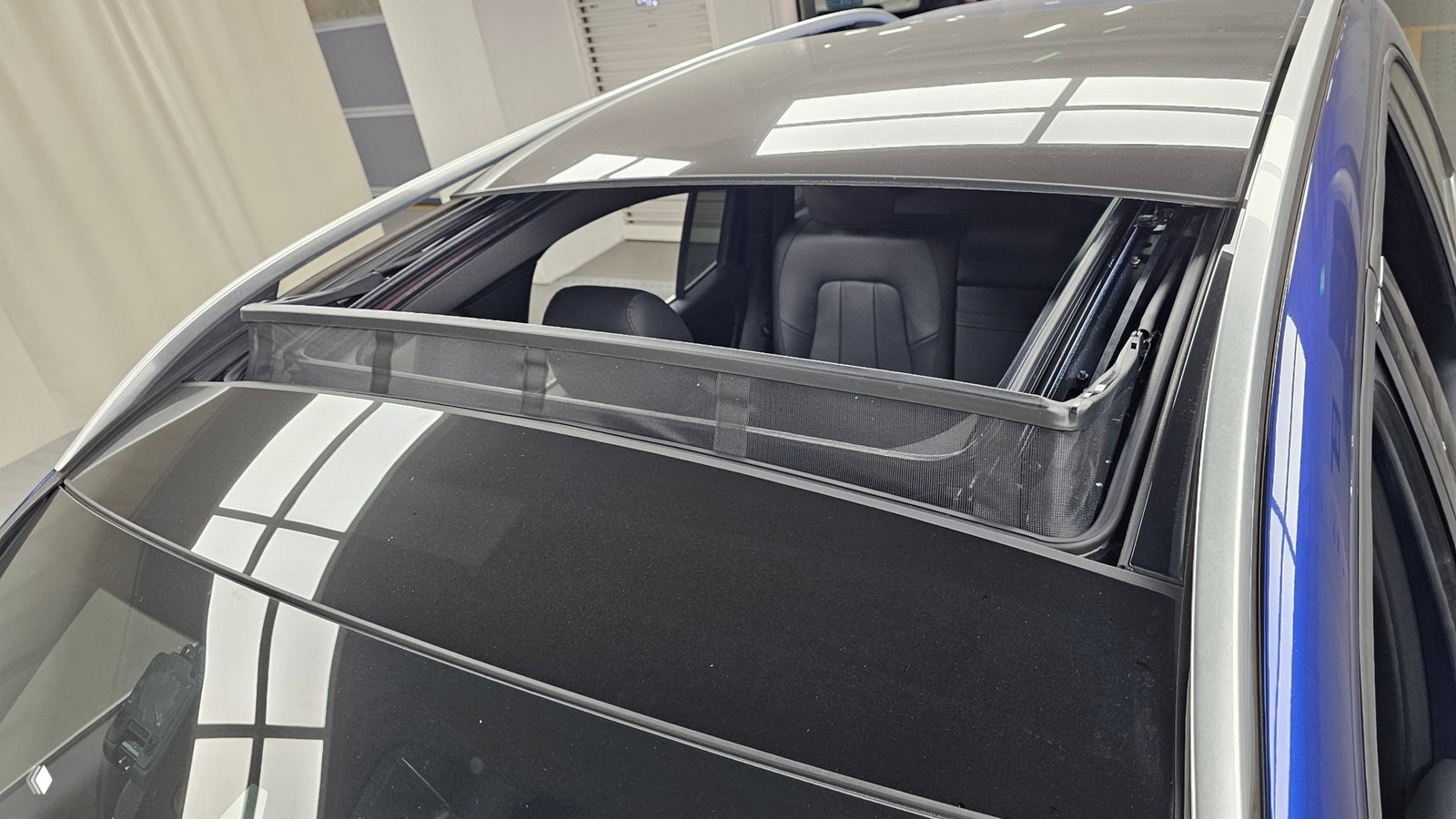 Панорамный люк Mercedes GLB в открытом положении: видна сетка солнцезащитного экрана, часть крыши и верхняя секция салона с освещением.