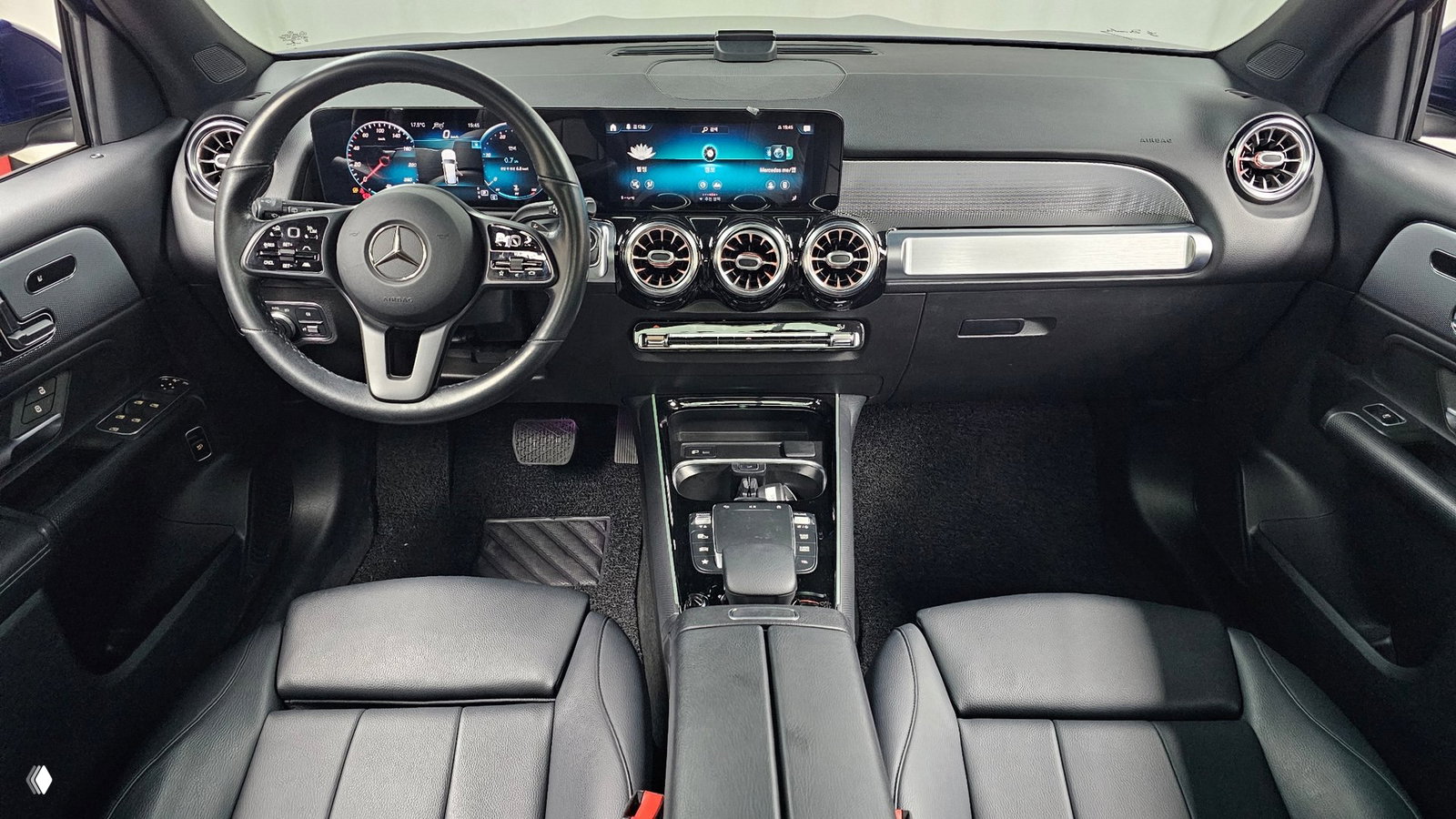 Интерьер Mercedes GLB: руль с эмблемой, цифровая панель приборов и широкая мультимедийная панель с воздуховодами и кожаной отделкой сидений.