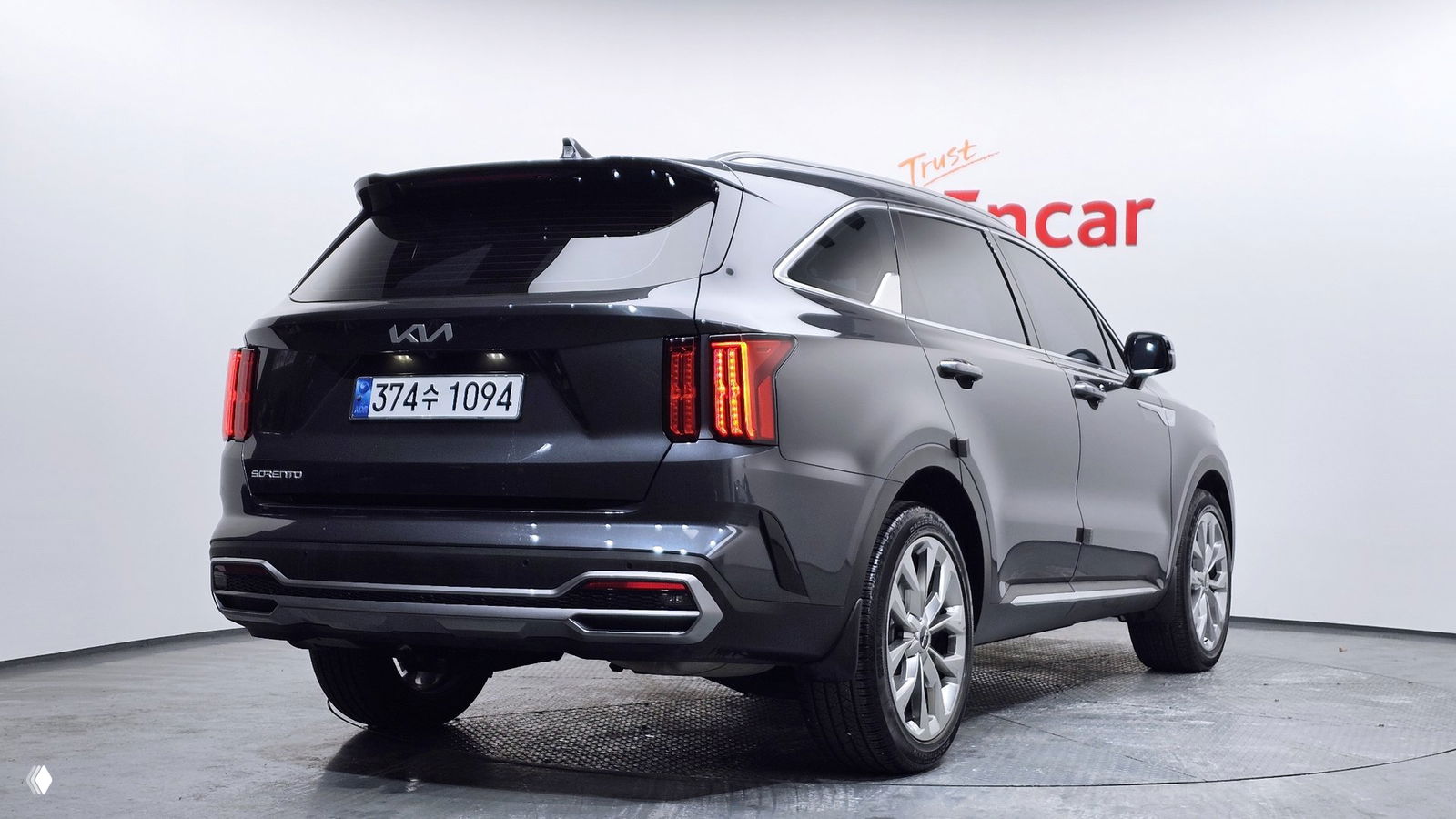 Kia Sorento четвёртого поколения серого цвета в студии Encar, вид сзади‑сбоку; видна вертикальная задняя оптика, корейская номерная табличка и задний бампер.