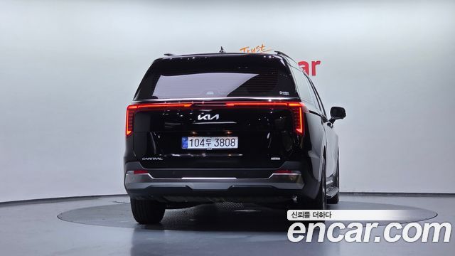 Ещё один задний кадр Kia Carnival HEV 2025 на поворотном подиуме Encar, подчёркнуты фонари и форма кормы автомобиля.