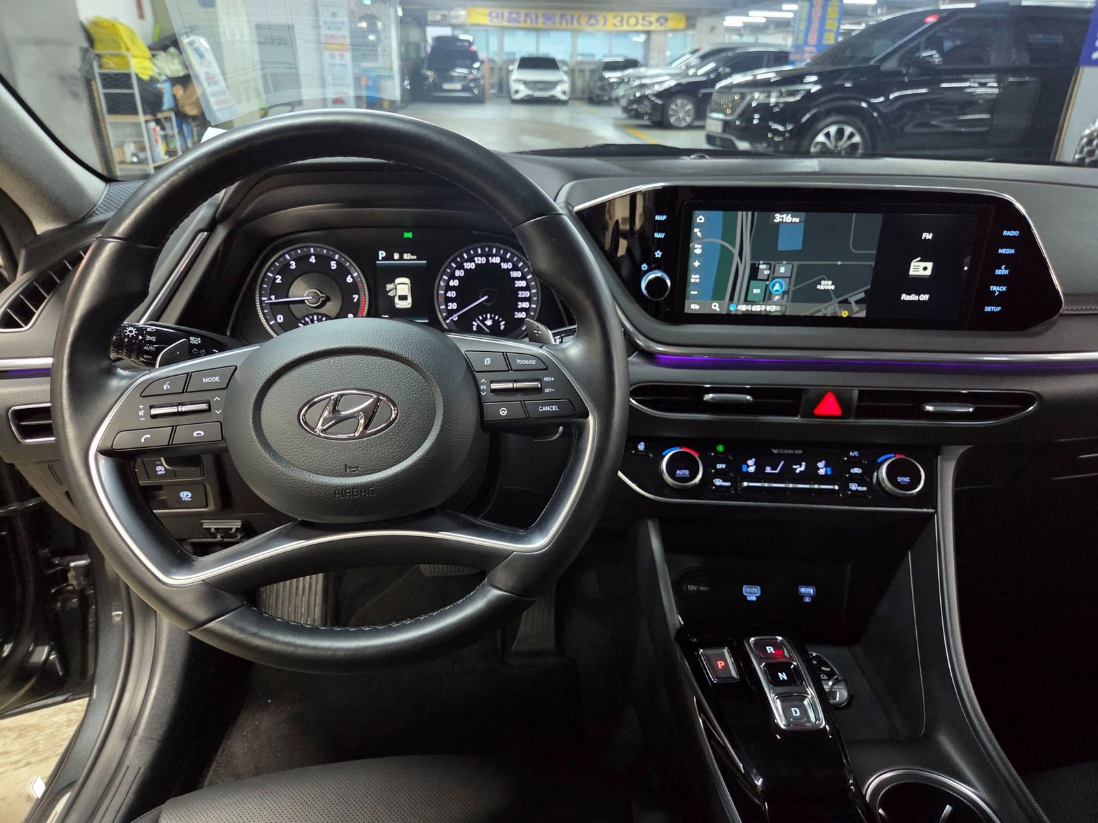Интерьер и панель приборов Hyundai Sonata 2021: рулевое колесо, цифровая приборная панель и мультимедиа с навигацией, салон в парковочном боксе в Корее.