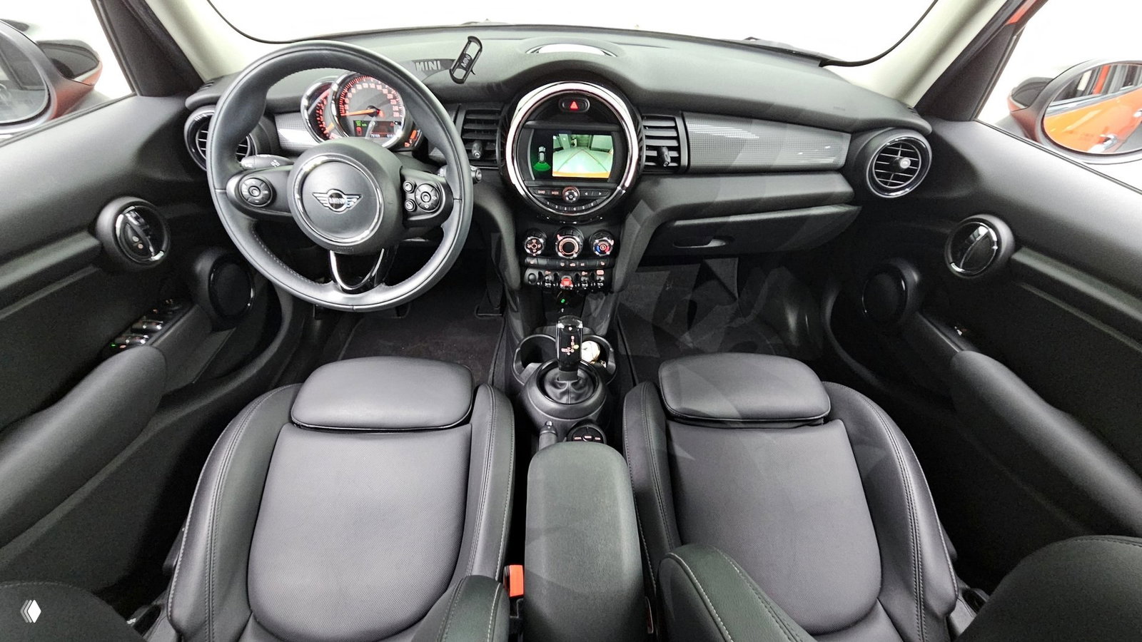 Салон Mini Cooper 2021: панель приборов с логотипом MINI, руль, центральная консоль и передние кресла — общий вид интерьера.