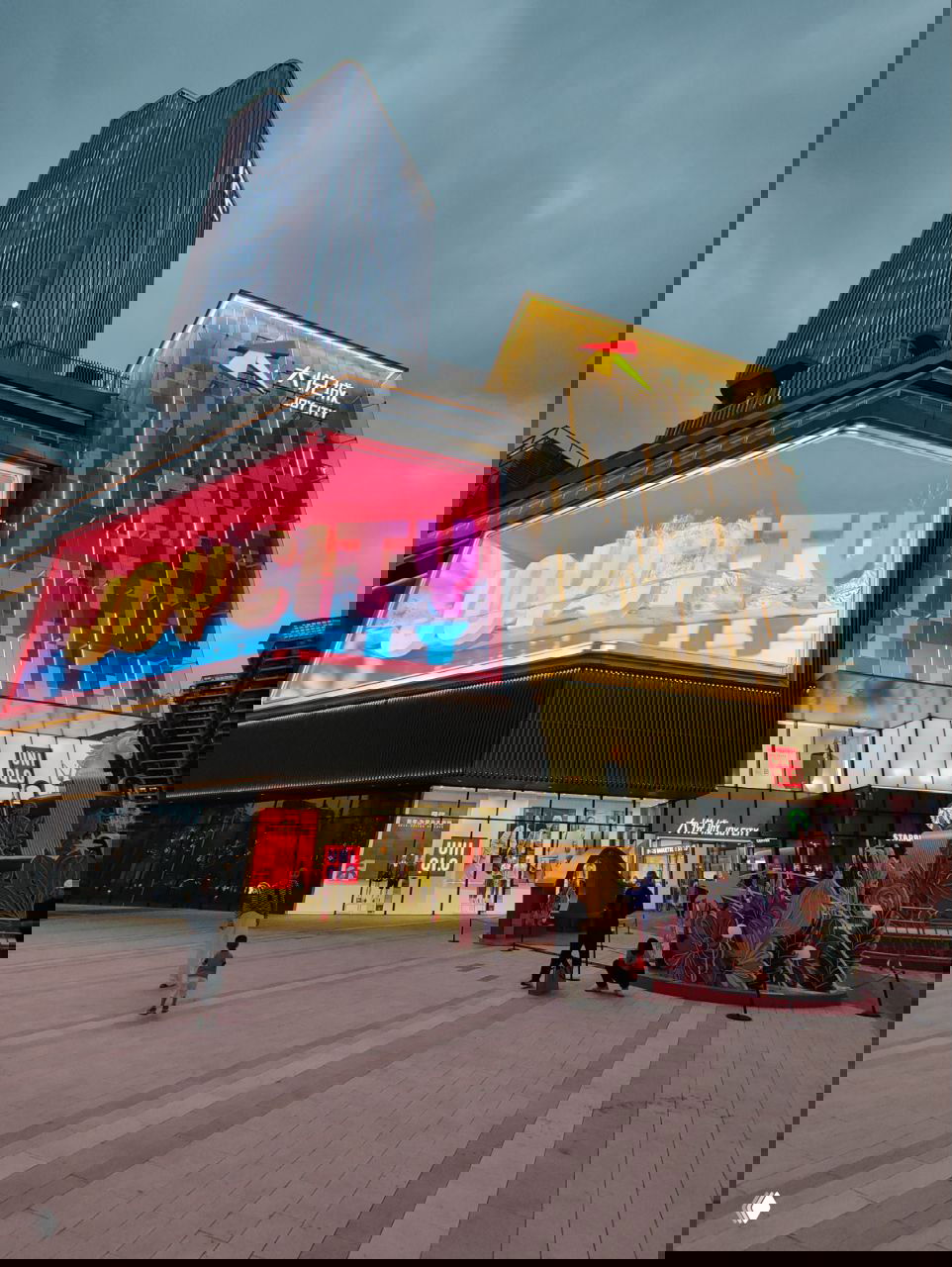 Современный торговый центр с крупным неоновым экраном JOYCITY; фасад и витрины магазинов в вечернем освещении крупного китайского города.