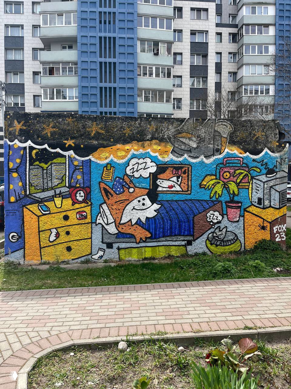 Граффити на бетонной стене: спящий лис в пижаме на кровати, ночное небо со звёздами, шкаф и растения на переднем плане.