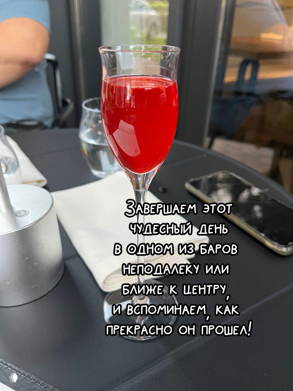Бокал с ярко‑красным напитком на уличном столике в баре — финальное фото дня и тёплая атмосфера завершения прогулки.
