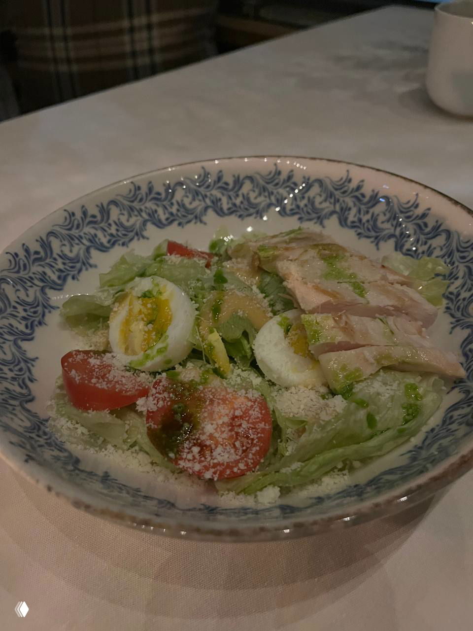 Салат в глубокой тарелке: зелёные листья, перепелиные яйца, помидоры черри и тёртый сыр — лёгкое и домашнее блюдо в меню ресторана.