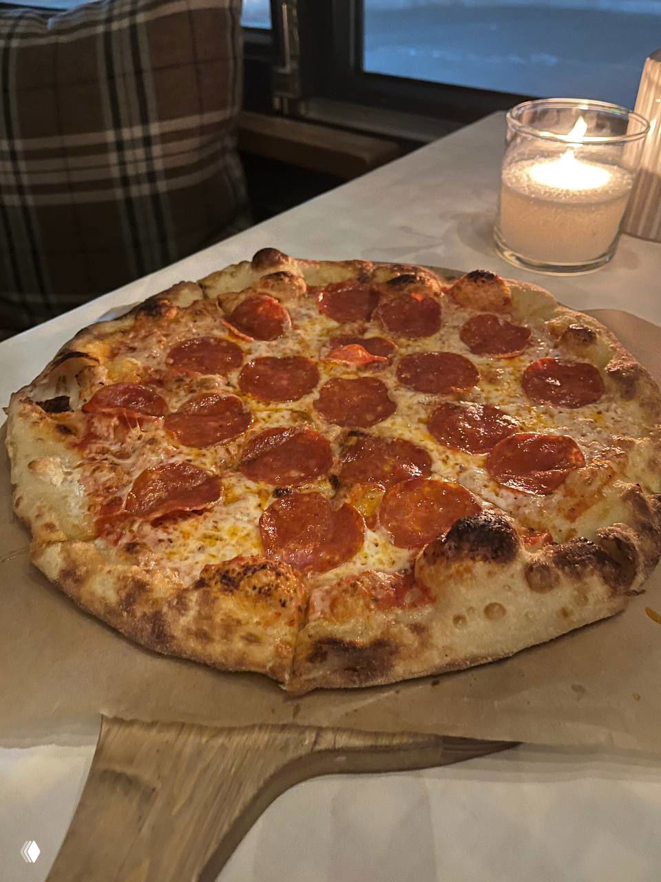 Дровяная пицца пепперони на деревянной доске с золотистой корочкой, расплавленным сыром и ломтиками пепперони на верхушке.