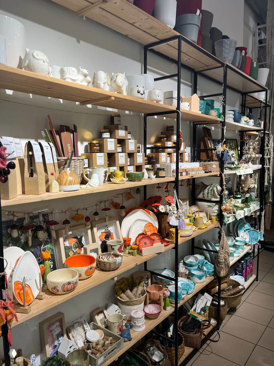 Стеллажи с сувенирами и керамикой: чашки, тарелки и небольшие подарки от калининградских мастеров в уютном магазине у парка