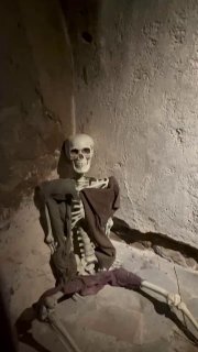 Манекен-скелет в мрачном подвале квест-экскурсии «Проклятие епископа» в замке Тапиау, сценография с приглушённым светом и каменными стенами.